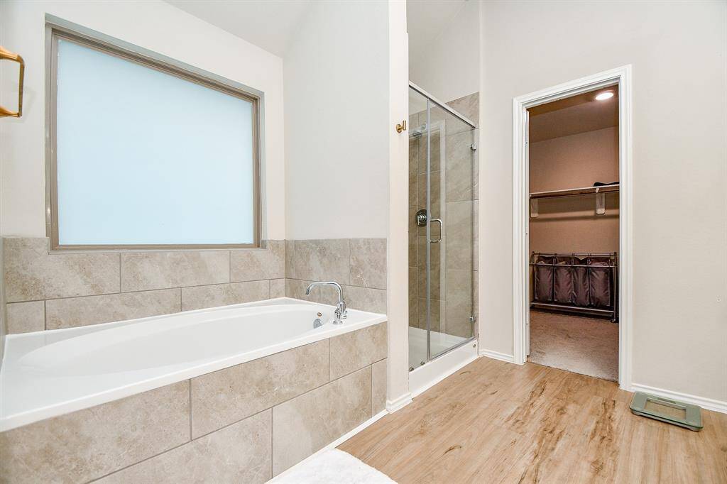 The primary bathroom is a luxurious spa-like retreat. Featuring a large, soaking tub perfect for unwinding, it’s complemented by a walk-in shower with elegant tile work and modern fixtures.