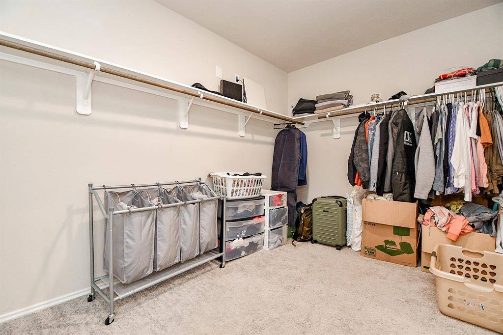 The primary walk-in closet is a spacious, organized haven for your wardrobe. With plenty of room to hang, fold, and store, it features custom shelving and hanging rods designed to maximize space. The high ceilings add to the sense of openness, while built-in shelves and drawers offer convenient storage for accessories and shoes. With thoughtful design and ample space, this walk-in closet ensures your belongings are neatly arranged and easily accessible, making it a practical yet luxurious.