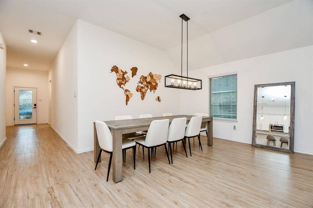 Large windows allow natural light to flood the room, enhancing the airy ambiance. The neutral color palette and elegant finishes, including stylish lighting fixtures, create a sophisticated yet comfortable setting.