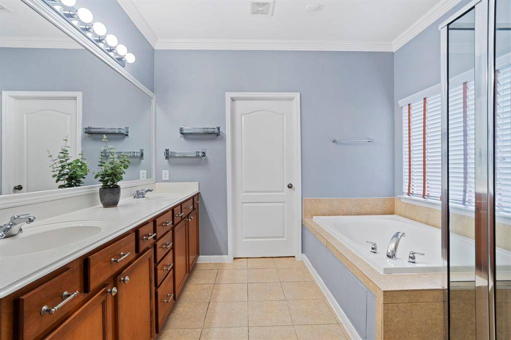 Spa-like owner's ensuite bath features a large dual vanity, a soaking tub, separate glass shower, linen closet, private water closet, and an expanded walk-in closet.
