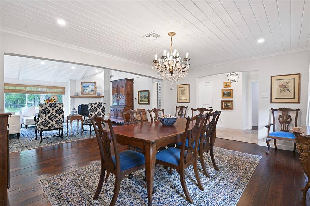 The spacious formal dining room features warm engineered hardwood floors, recessed lighting, tongue and groove shiplap ceilings, custom window treatments, and an antique crystal chandelier.