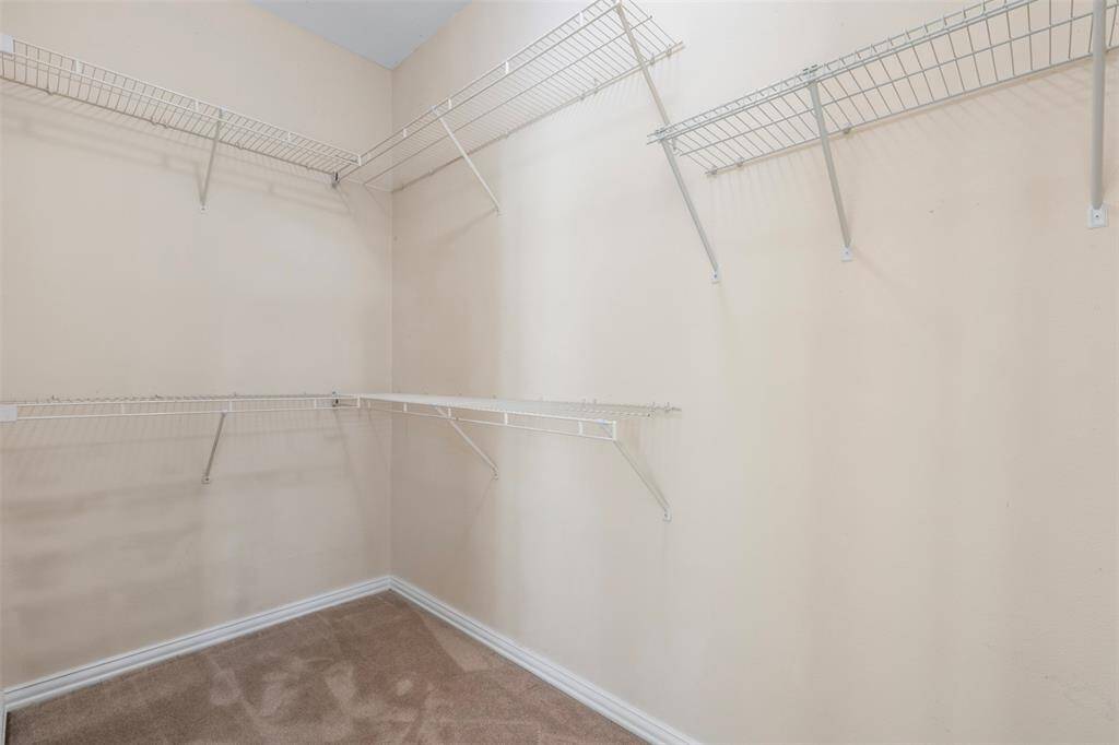 Primary bedroom walk-in closet with built-in shelves