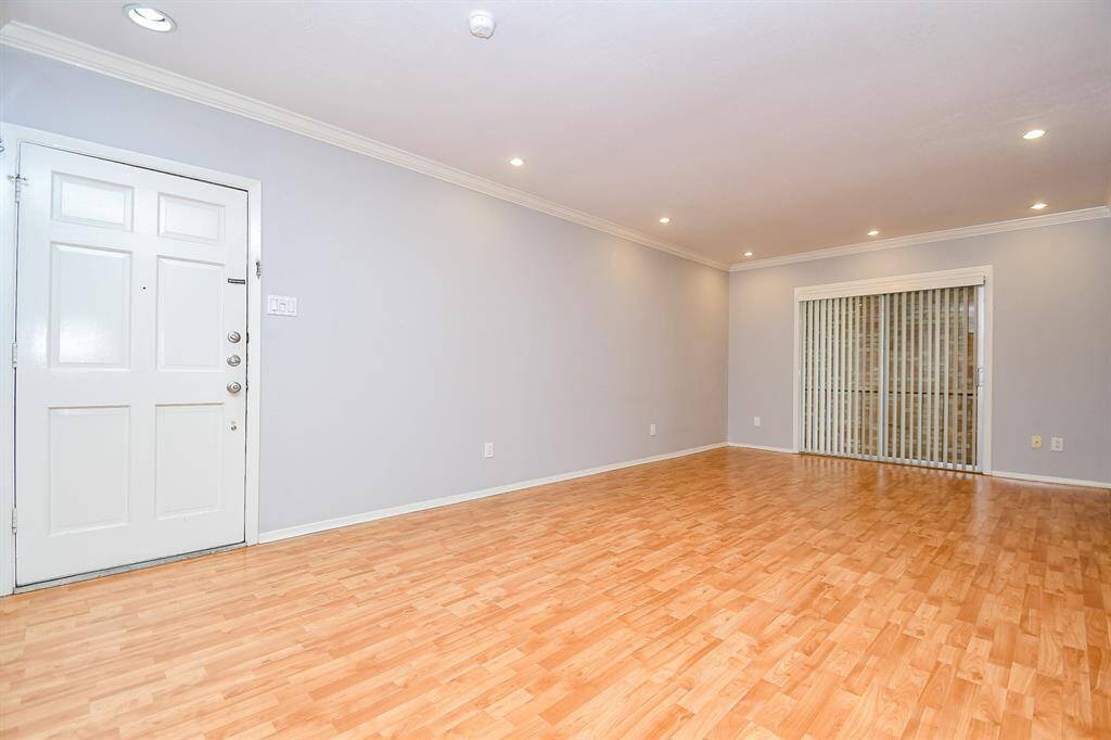 Another view of the living space shows the abundance of space, stylish flooring & the front door leading out to the second floor entry to the condo.