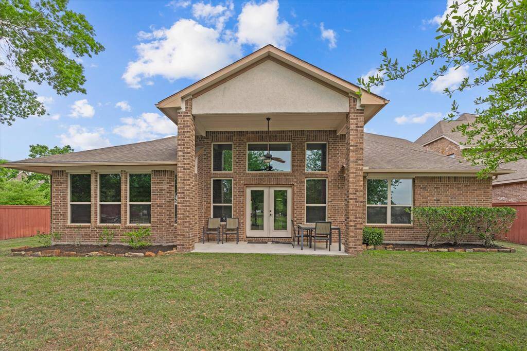 This photo showcases a spacious brick home exterior with large windows and a covered patio area, ideal for outdoor relaxation. The surrounding yard is well-maintained, offering ample space for gardening or recreation.