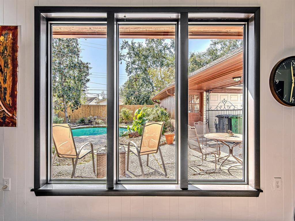 Expansive living room windows frame a serene view of the backyard oasis, complete with a pool and outdoor seating, creating a seamless connection to nature.