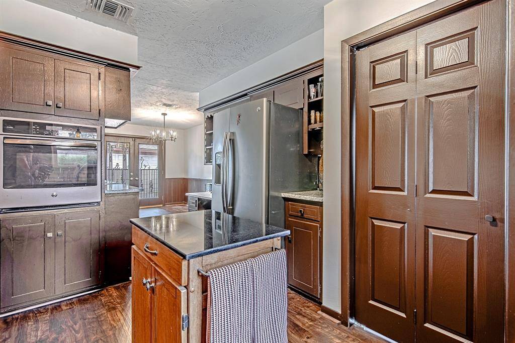 Kitchen includes a convenient wet bar area flanking the refrigerator, with easy access to the pantry and laundry room through the adjacent door, offering both functionality and style.