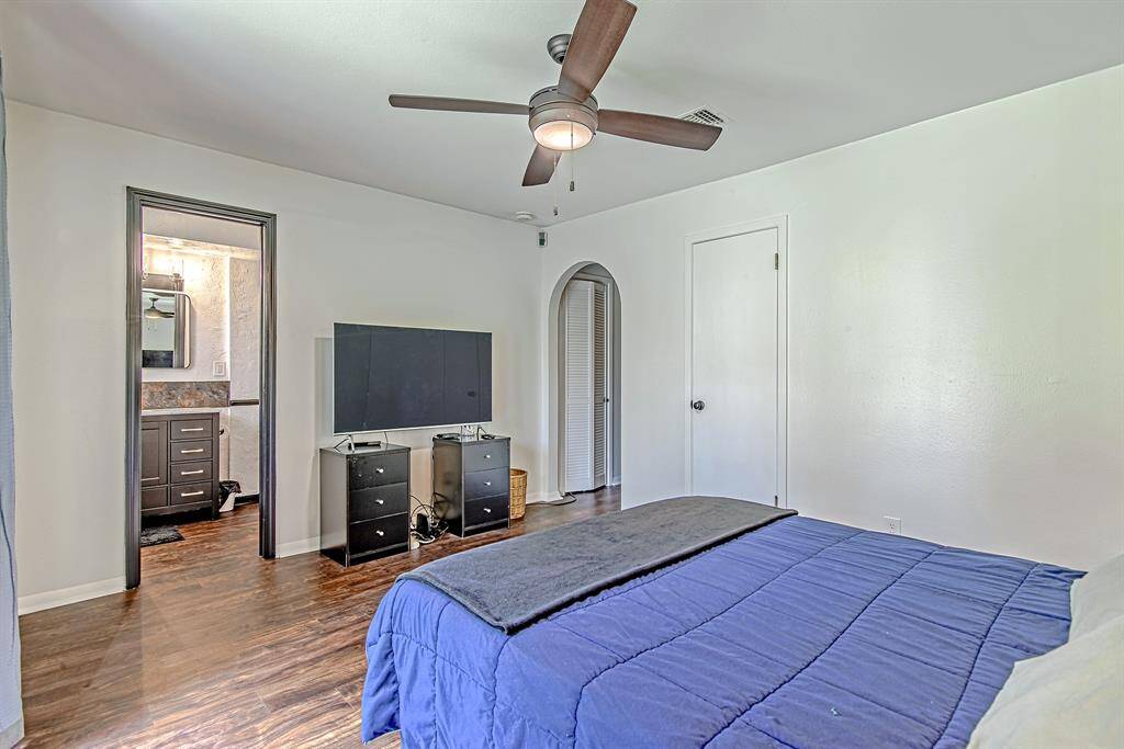 Primary bedroom offers an ensuite bathroom, ample storage with a dedicated closet and two additional closets in the hallway, all accessed through a charming arched doorway.