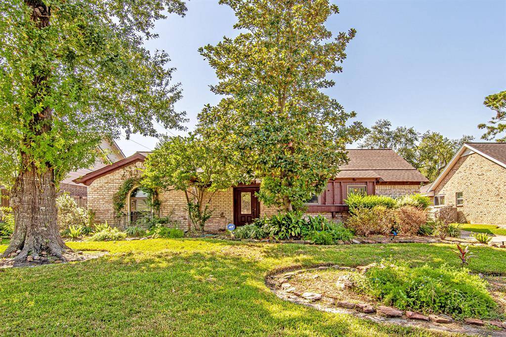 Charming brick exterior surrounded by lush landscaping, featuring mature trees that offer shade and privacy in this sought-after Lazybrook neighborhood.