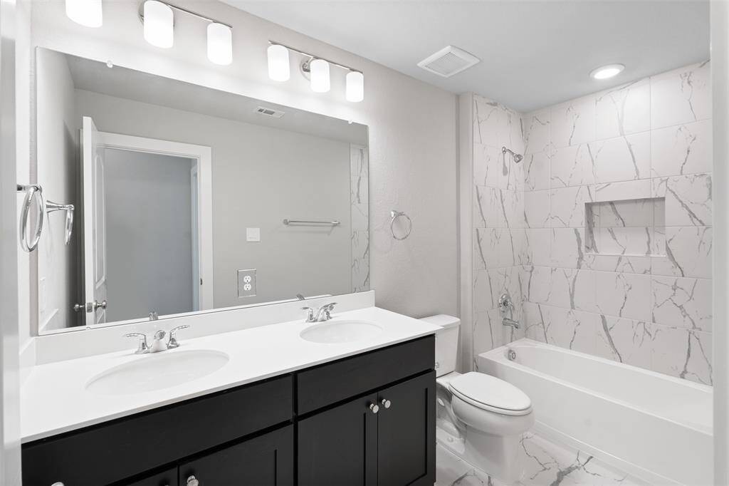 Full bath with double vanity sinks, shower/tub combo with built in niche