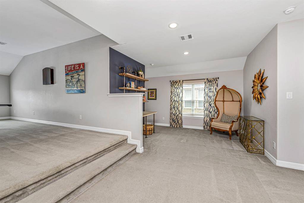 Large upstairs game room with high ceilings, neutral tones, and space for a pool table, ping pong, or media setup. Multiple windows provide abundant natural light and views of the backyard.