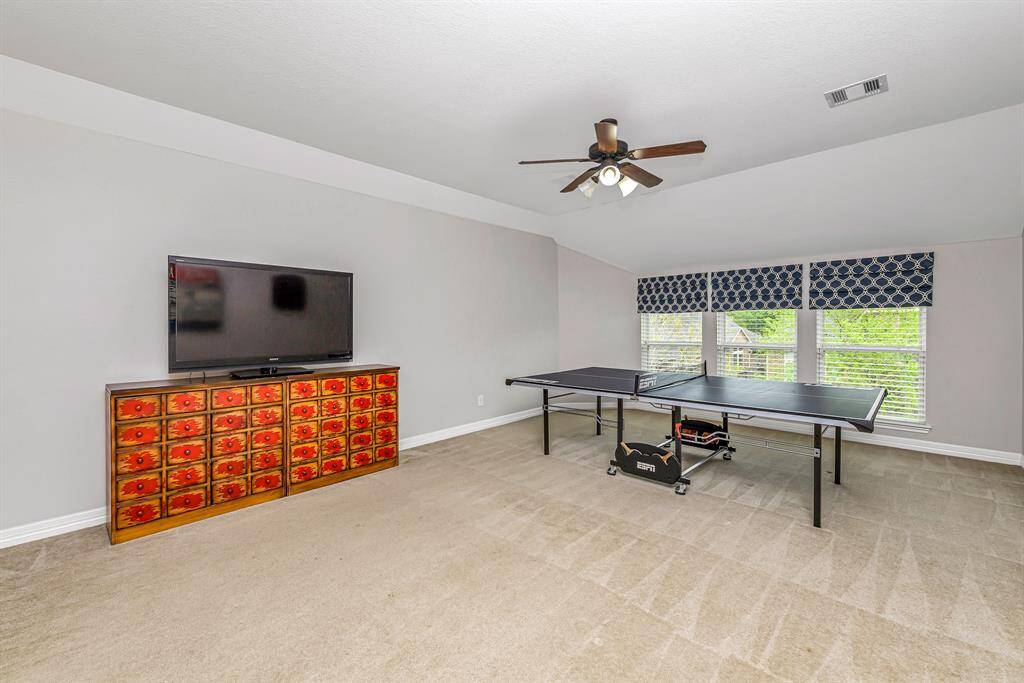 A second view of the game room highlights the open layout and direct access to the upstairs landing. Perfect for casual entertaining, movie nights, or game-day gatherings.