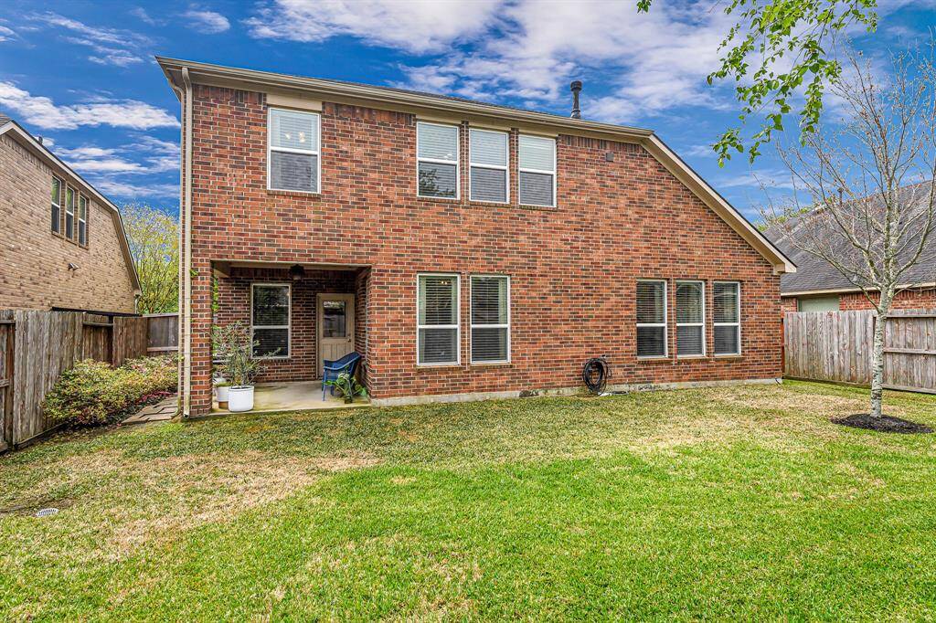Spacious fenced backyard with a covered patio and plenty of green space for pets, play, or gardening. Brick exterior and mature landscaping offer privacy and durability.