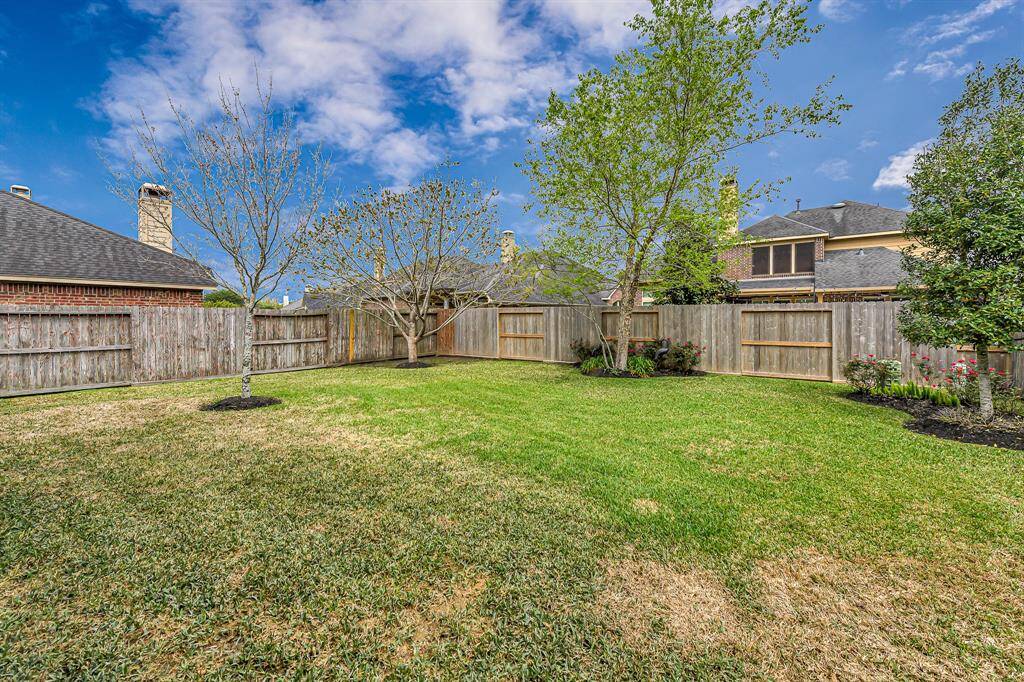Spacious fenced backyard with a covered patio and plenty of green space for pets, play, or gardening. Brick exterior and mature landscaping offer privacy and durability.