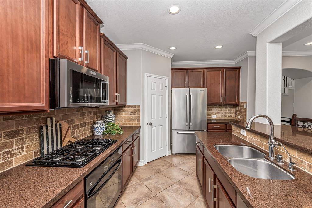 Open-concept kitchen overlooks the breakfast area and family room, creating seamless flow throughout the main living space. Rich cabinetry, granite counters, and designer lighting add warmth and style to this everyday gathering hub.