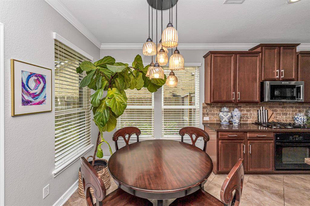 Bright and cozy, the breakfast nook features statement lighting, windows with custom blinds and backyard views. It connects seamlessly to the kitchen for easy meals and casual dining.