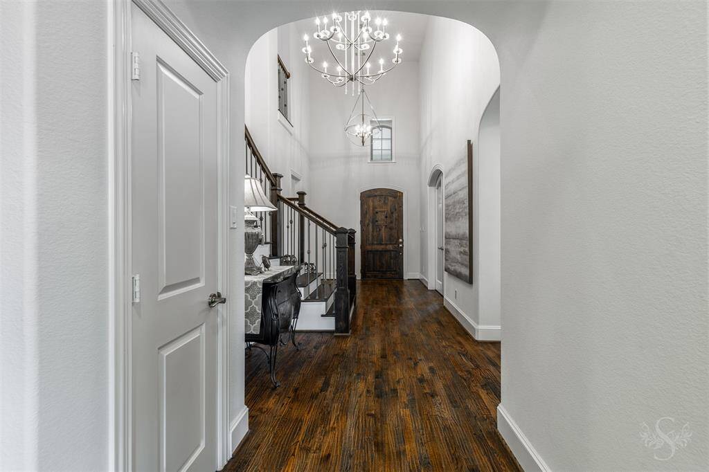 The grand entry of this home showcases stunning hand-scraped wood flooring and a lovely chandelier that adds elegance to the space. With its soaring high ceiling, it creates an impressive first impression, setting the tone for the rest of the home.
