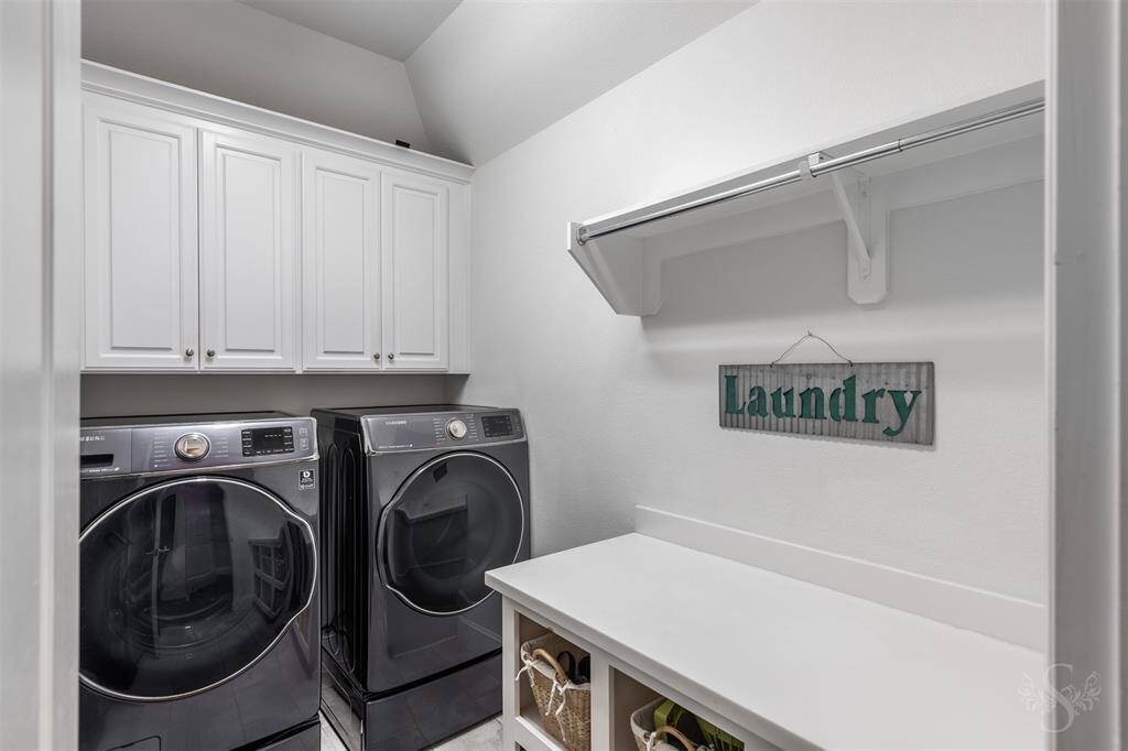 This spacious laundry room is equipped with cabinets for storage and rods for hanging clothes, keeping everything organized and accessible. With plenty of counter space to fold laundry, it’s a practical and efficient area to manage household tasks.