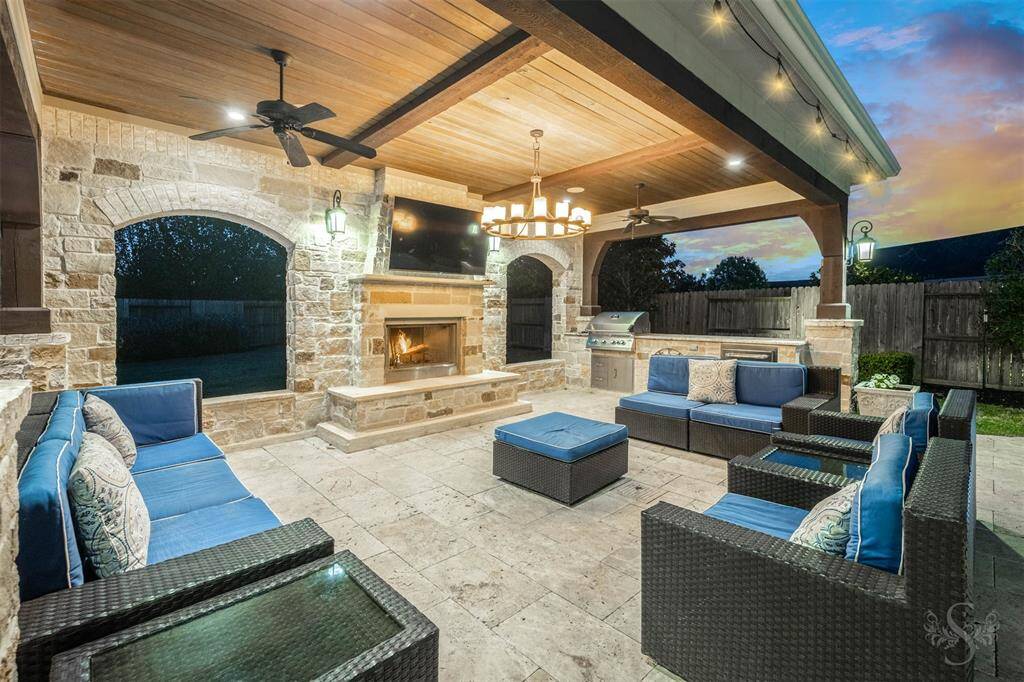 Elevate your outdoor living experience with this luxurious covered patio, thoughtfully designed for upscale entertaining. An outdoor kitchen makes hosting effortless, while the elegant stone fireplace creates a warm, inviting ambiance. Designer lighting, including a statement chandelier, and ceiling fans enhance both comfort and style. This is outdoor living redefined—where every gathering feels like a private resort experience. Plumbed gas grill (no bottles).
