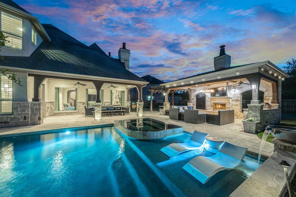 Experience resort-style living under the stars in this exceptional outdoor retreat. Designed for both grand entertaining and intimate relaxation, the space features two expansive covered patios - one showcasing a stunning stone-surround fireplace and an outdoor kitchen, perfect for evening gatherings. The second offers generous room for elegant dining and lounging under the recessed lighting. Just steps away is a sparkling pool and spa creating a serene, private oasis where luxury meets leisure.