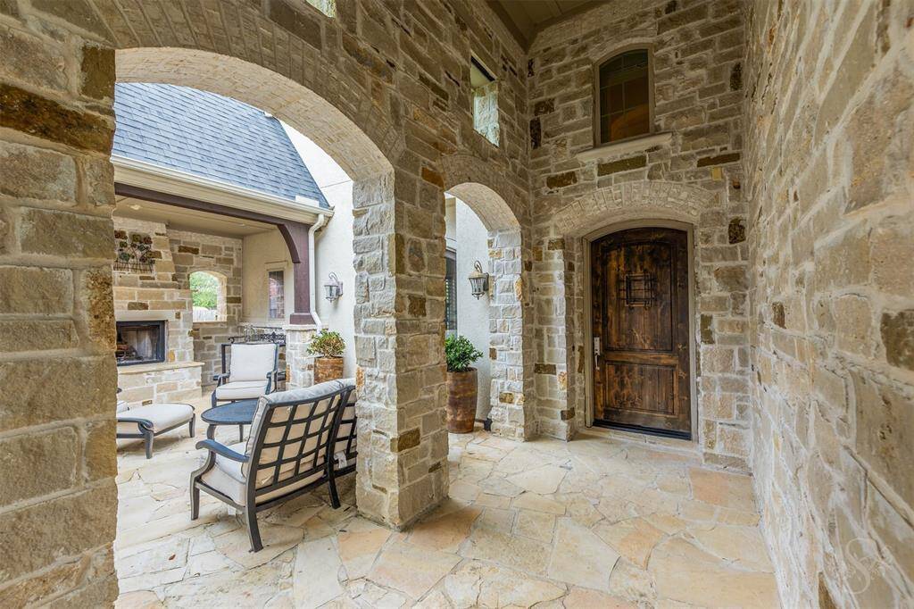 An elegant outdoor courtyard sets the stage for gatherings around a natural stone fireplace, offering a cozy and welcoming atmosphere. With plenty of space for comfortable seating, this outdoor area boasts  rustic elegance with relaxed comfort, creating the perfect spots to unwind or greet guests in style.