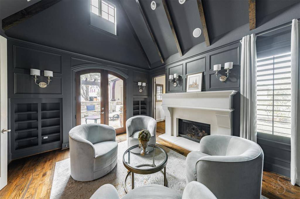 The home study is a sleek yet cozy retreat, featuring custom gray walls that set a sophisticated tone against rich wood flooring. Featuring a high vaulted ceiling with wood beams, custom built-ins, and double doors leading out to the private courtyard in front of the home, making it the perfect spot for work, reading, or simply unwinding.