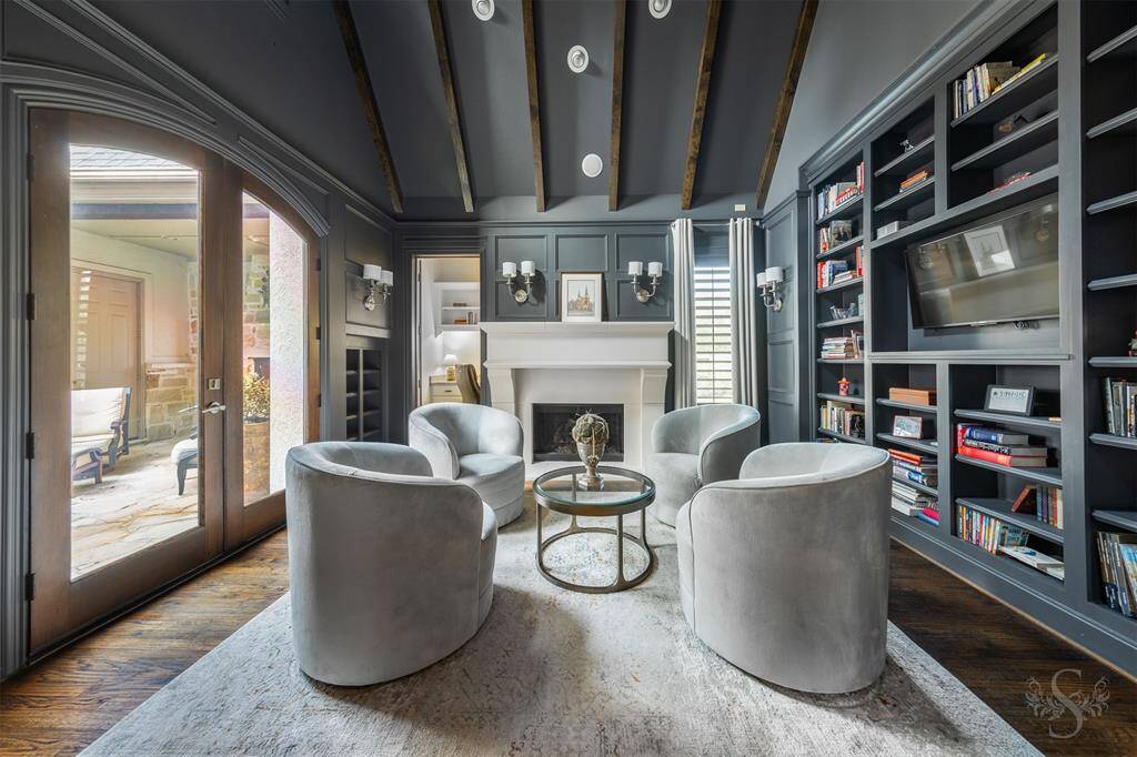 The home study is a sleek yet cozy retreat, featuring custom gray walls that set a sophisticated tone against rich wood flooring. Featuring a high vaulted ceiling with wood beams, custom built-ins, and double doors leading out to the private courtyard in front of the home, making it the perfect spot for work, reading, or simply unwinding.