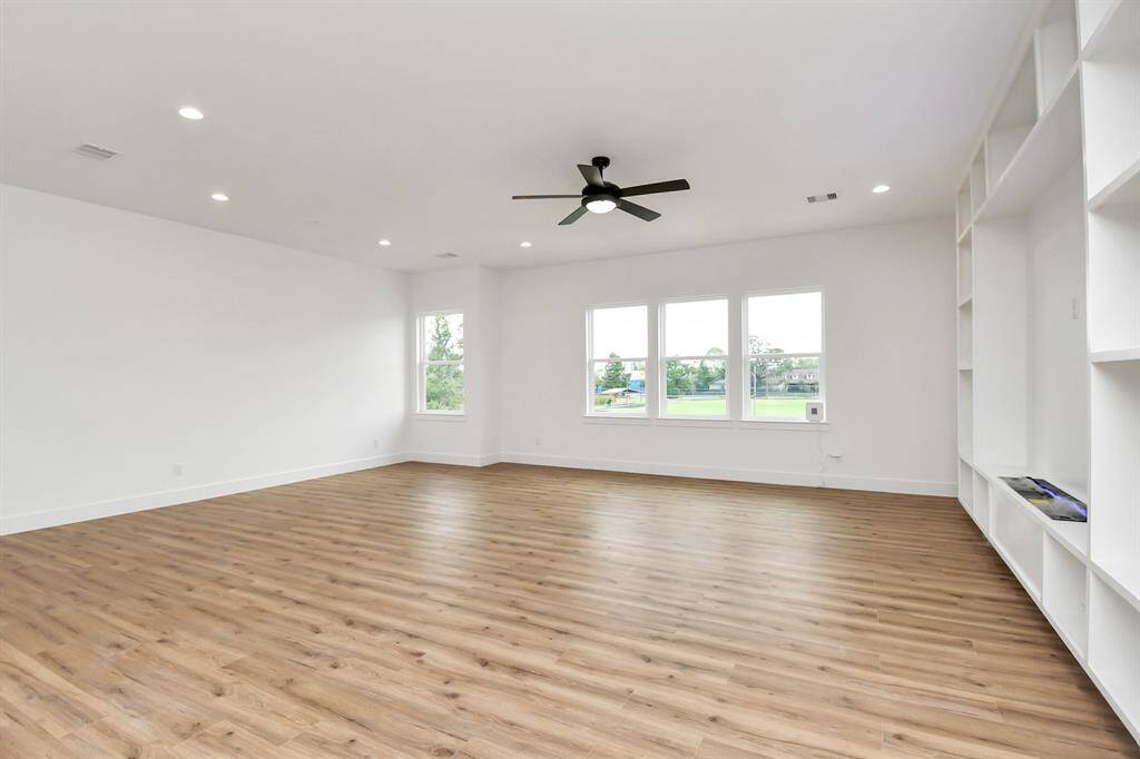 Welcome family and guests to your charming living room! With its high ceilings, recessed lighting, ceiling fan, custom paint, beautiful flooring, and large windows that let in abundant natural light, this room is perfect for gatherings.
