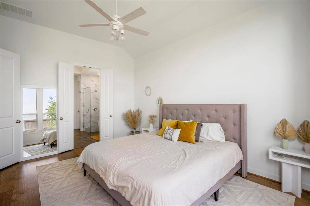 This stunning primary bedroom blends cozy comfort with modern elegance — featuring calming hues, a modern chandelier, wood floors, high ceilings, and direct access to the primary bathroom. A true retreat to relax, recharge, and unwind.
