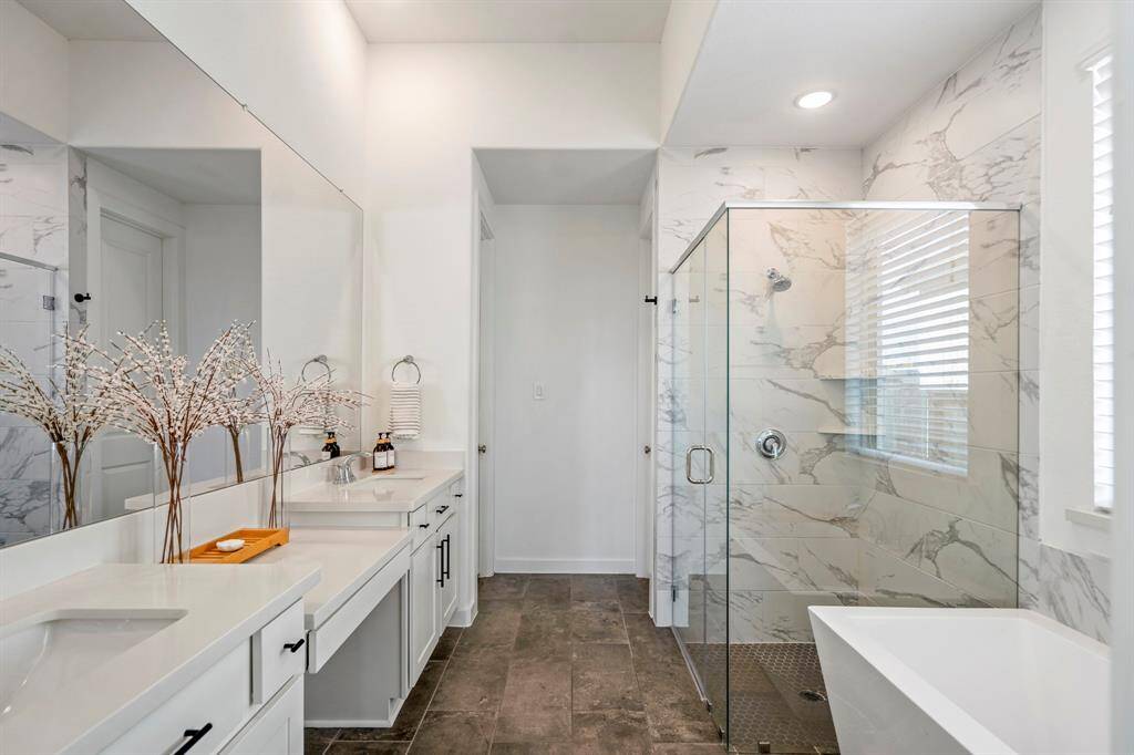 Experience luxury in this expansive primary bathroom, complete with a stunning freestanding tub, walk-in shower, sleek quartz countertops, and contemporary tile accents — the perfect oasis for relaxation and rejuvenation.