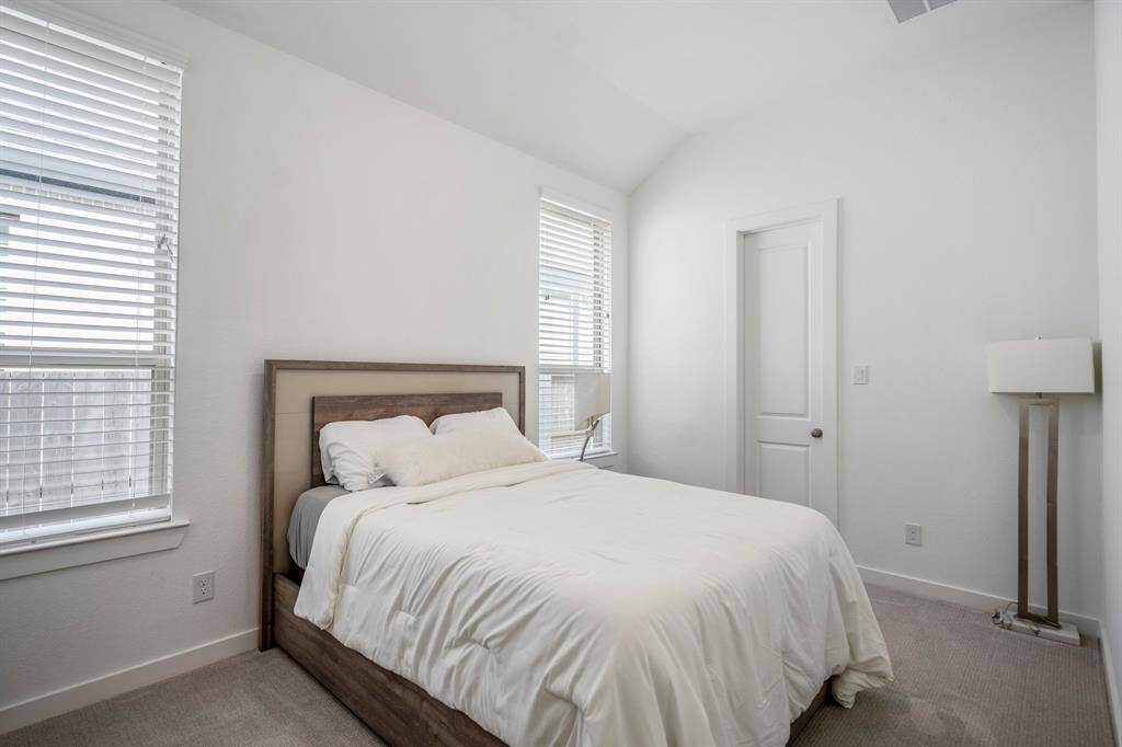 Tucked down a private hallway is the first of the spacious secondary bedrooms which features plush carpet, high ceilings, bright natural light, and a spacious closet.
