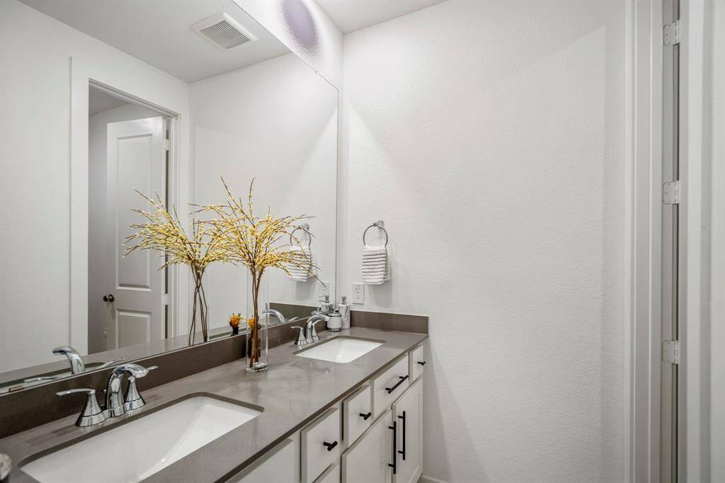 Located between the last secondary bedrooms, this full bathroom offers additional privacy with a separated vanity and shower making it easy to share and get ready! It features with white cabinets, gray quartz countertops, a spacious tub and shower, dual sinks, and large mirror.