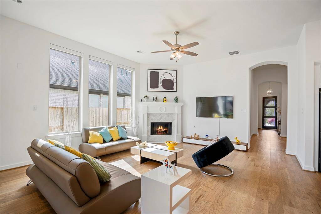 Whether it's a simple night in or entertaining family and friends, this home has ample open space for everyone to enjoy! Featuring a modern, sleek ceiling fan, recessed lighting, and luxurious wood floors this living space offers it all.