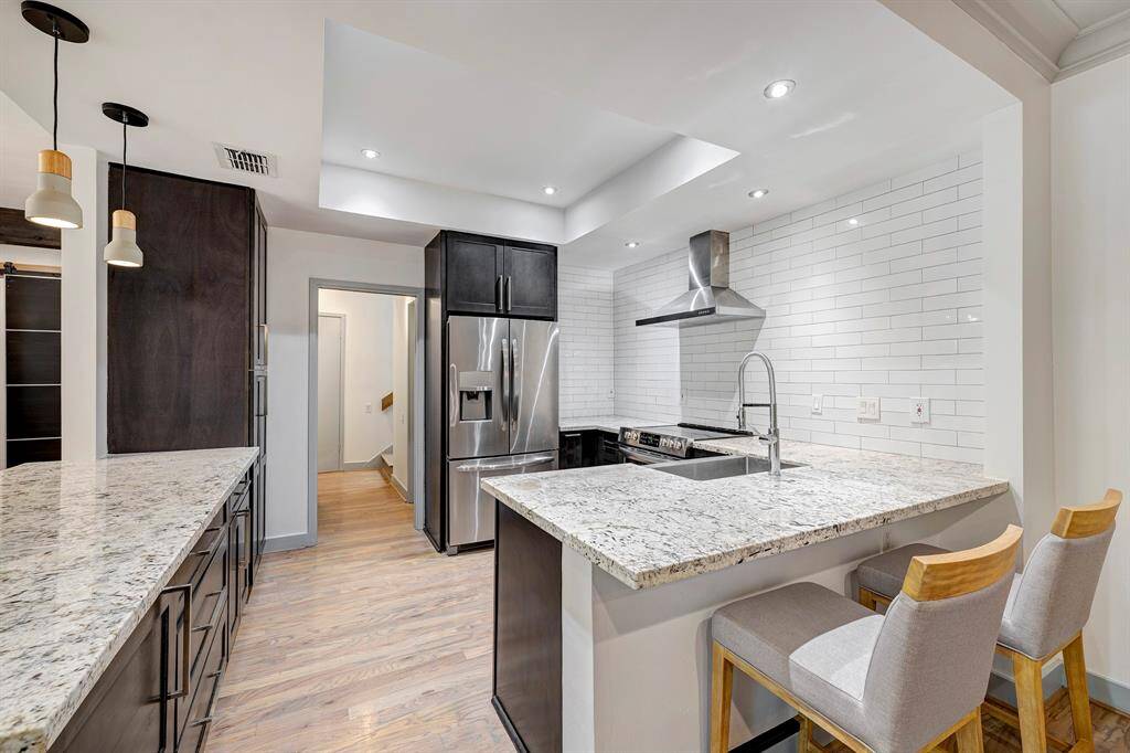 Concealed microwave is in cabinet on the left.  Stylish white subway tile stretches to the ceiling in this light and bright kitchen.