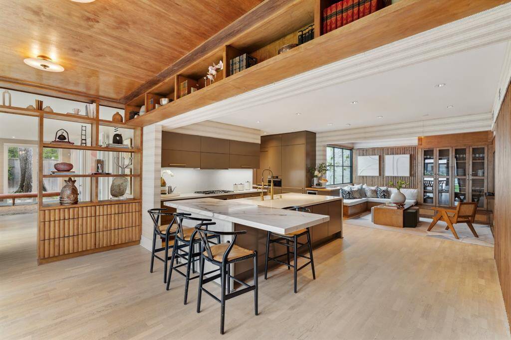 This KITCHEN is a masterpiece of thoughtful design. Large island w/quartz countertops & breakfast seating serves as the heart of the space. Ample storage is provided by electronic Poggenpohl cabinetry. Elegant Schumacher textured wallpaper, ribbed wood paneling w/hidden storage & open display shelves w/ maple wood & storage create a harmonious blend of warmth & sophistication. Designed for effortless living, the open floor plan connects to the den, making it perfect for entertaining & everyday moments.