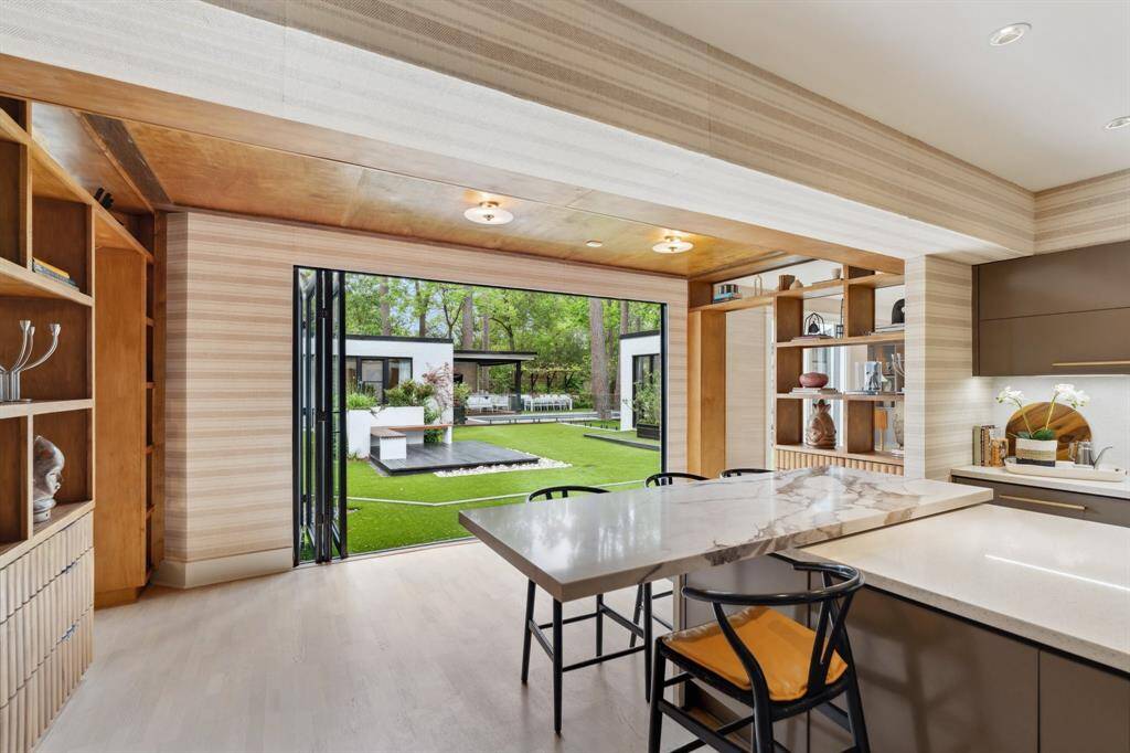 Expansive steel doors and windows slide completely open, blurring the lines between indoor and outdoor living while offering stunning courtyard views.