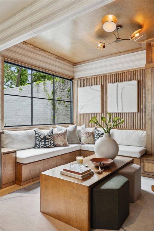 A newly installed expansive steel window (April 2025) frames serene views of the private front courtyard, filling the den with natural light.