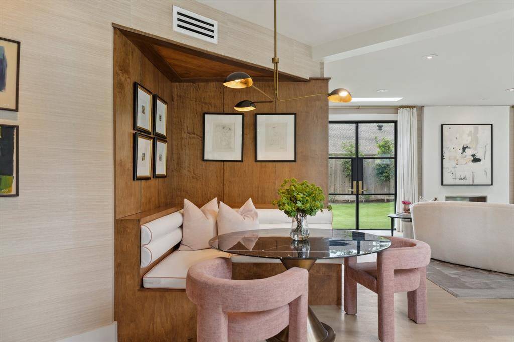 Bright and airy BREAKFAST room, conveniently located next to the kitchen and open to the family room is finished with maplewood paneling and a custom built in banquette. Large windows with drapes offer peaceful views of the courtyard. Finished with a stylish Visual Comfort light fixture.