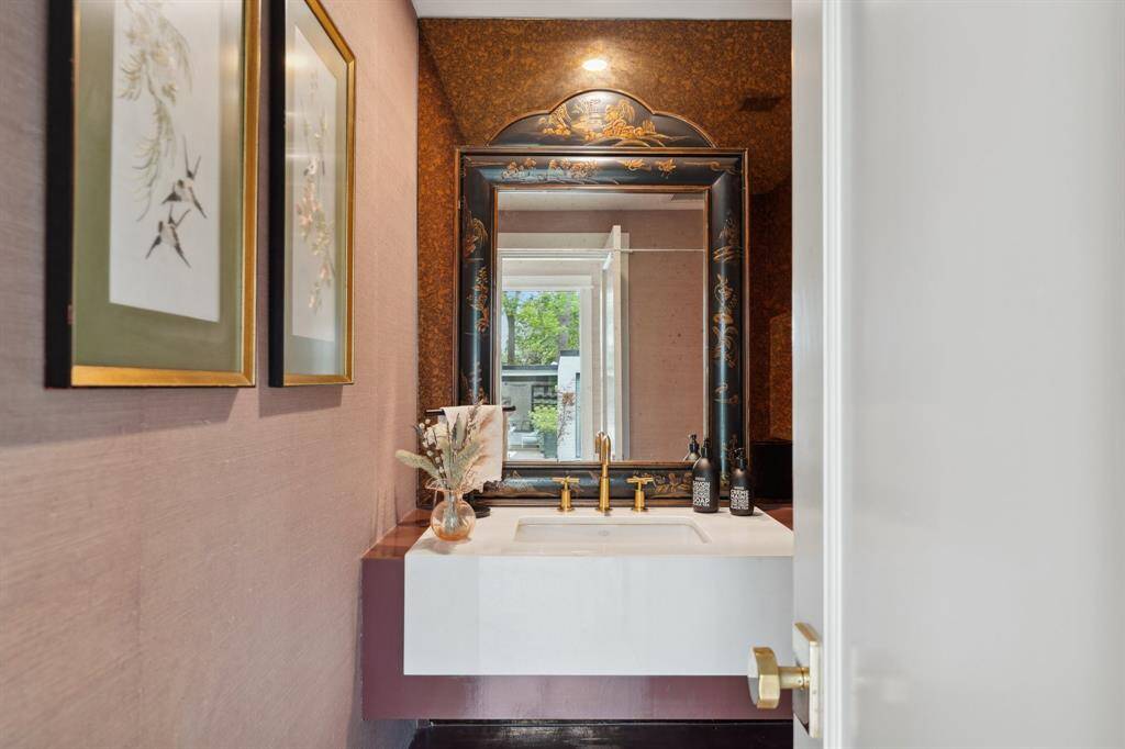 Elegant formal POWDER ROOM is conveniently located just off the entryway for guests. Features a floating vanity with a sleek quartz countertop, a stunning mercury glass accent wall, and Schumacher textured wallpaper for added sophistication.