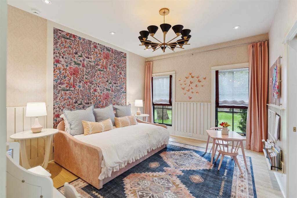 This charming SECONDARY BEDROOM #1 features Schumacher wallpaper and framed Vale London wallpaper, paired with drapes and window treatments. Note: decorative light fixture is excluded.