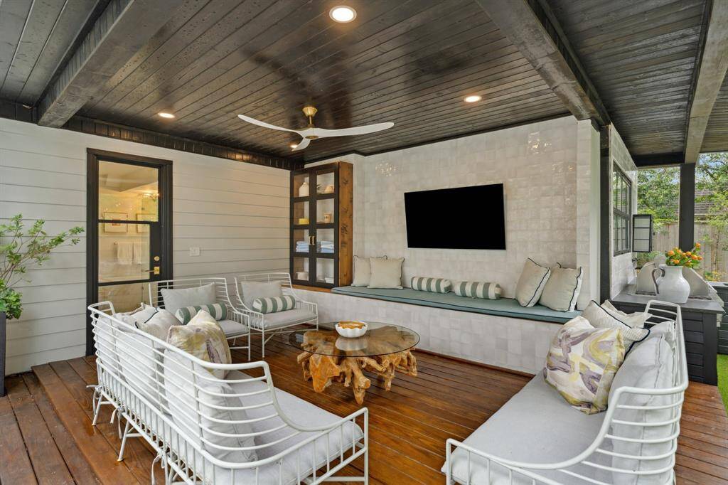 The covered patio features a ceiling fan, built-in bench seating, a decorative tile wall, and an outlet for an outdoor TV.  Perfect place to cool down after swimming and watch a game!
