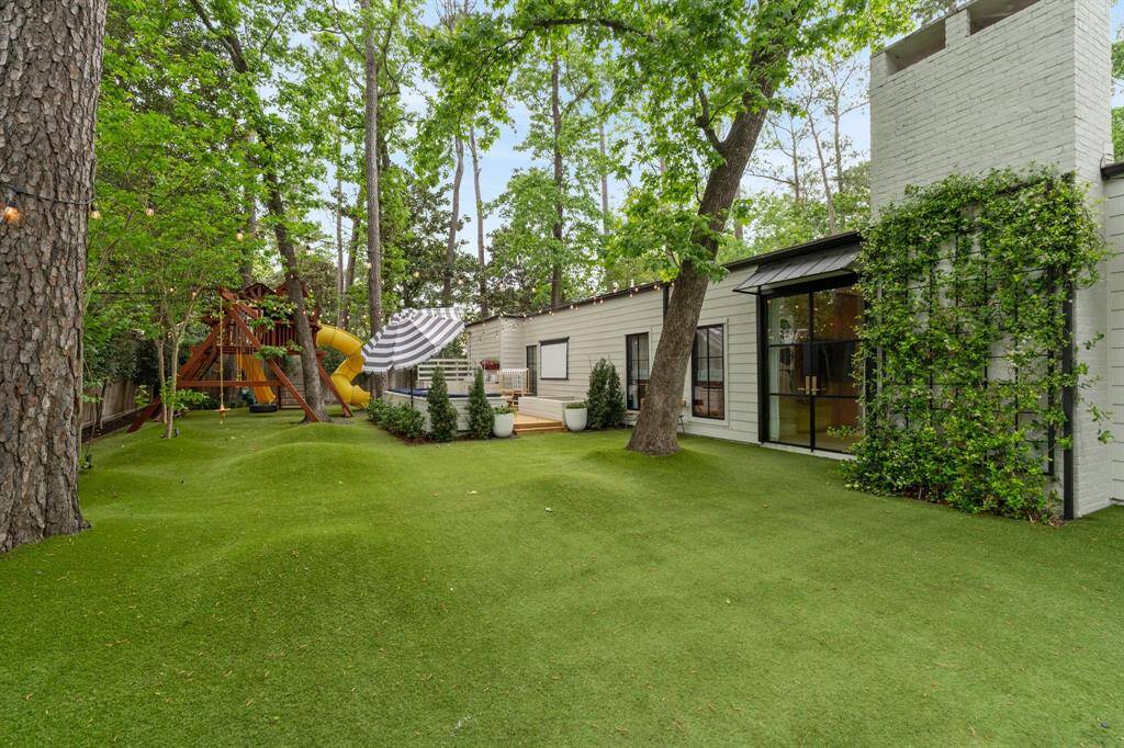 The spacious side yard off the family room is out of a kid’s dream, with extensive play space including a playhouse nestled in the trees, "hilly" turfed terrain, built-in bench seating, and a projector screen for movie nights. Additional thoughtful features include gutters with catch basins, a private driveway gate that opens to a turfed driveway offering ample space for a basketball goal, and a two-car attached garage with epoxy floors. The garage includes two large walk-in storage closets, four lockers, a