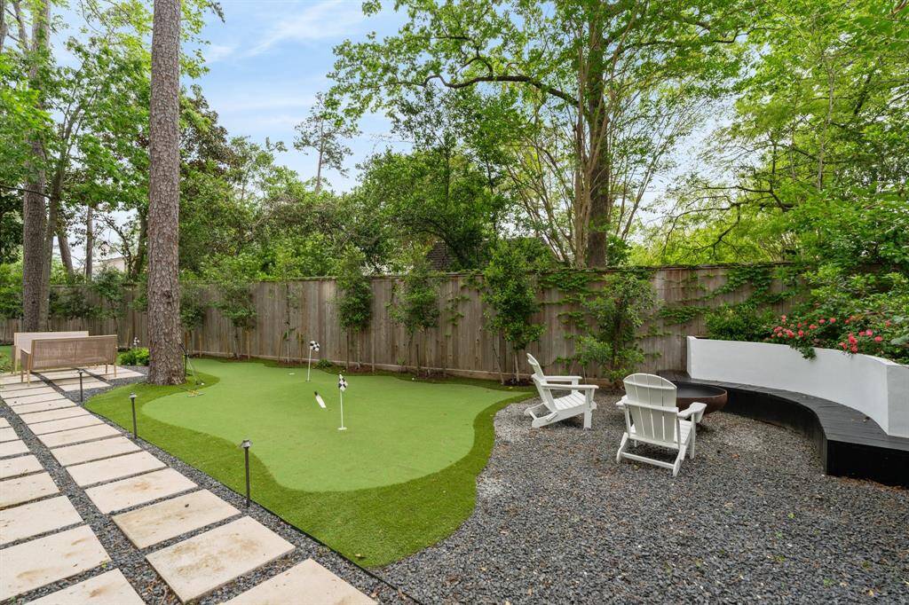 An expansive backyard continues and features a large turfed mini-golf area and a firepit.