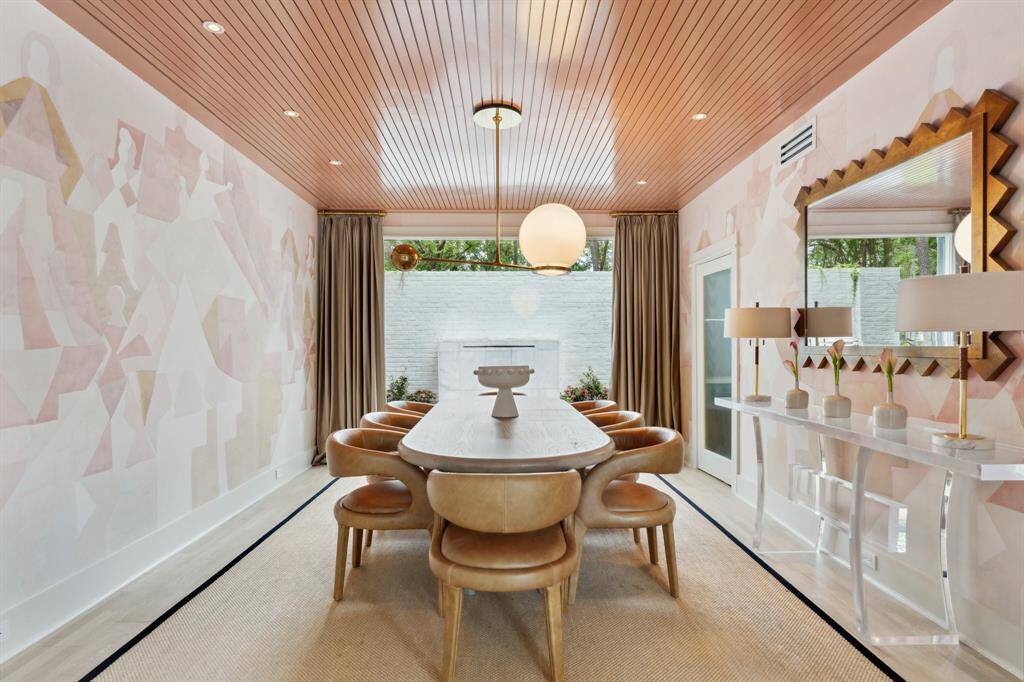 A striking DINING ROOM framed by elegant Schumacher wallpaper & reeded glass bifold doors, setting the stage for refined dining. Decorative Rejuvenation light fixture adds a touch of sophistication, while a large window overlooks the serene front courtyard & water feature. Spacious enough to accommodate a large dining table & buffet, this inviting space is perfect for hosting. A glass-reeded butler’s door provides seamless access to the kitchen & a beadboard ceiling treatment w/ can lighting completes the r