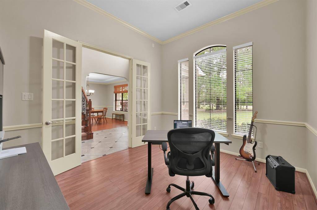 At the front of the home off the Foyer is the Study with 8' glass-panel French doors providing privacy and quiet, wood laminate flooring and crown molding. It overlooks the wooded and peaceful front yard helping make work more enjoyable.