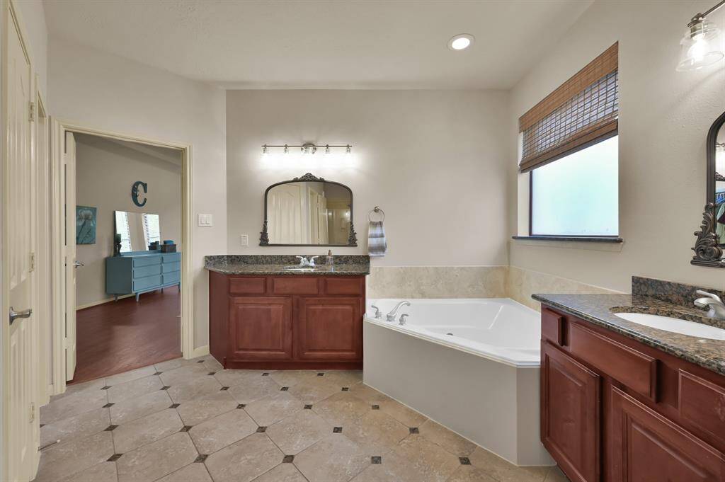 Two vanities, each with their own sink, make it easy for two people to get ready at the same time. Enjoy a relaxing soak in the tub with the frosted window and rattan Roman shade to regulate the light.