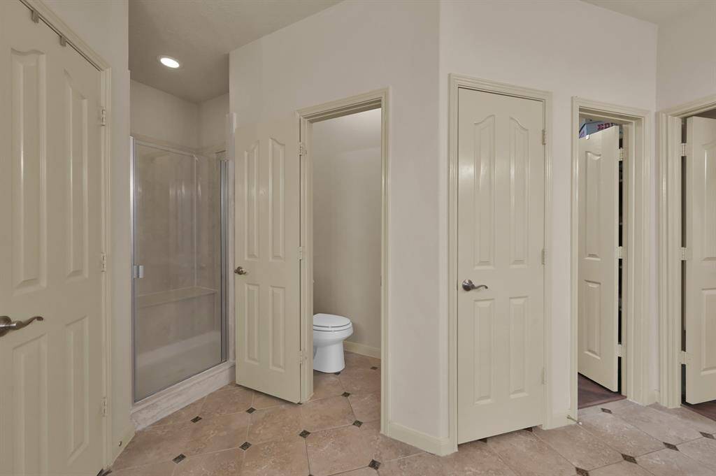 A separate shower with bench seat, water closet and an additional closet to store more needed bath items complete this Primary en-suite bath.