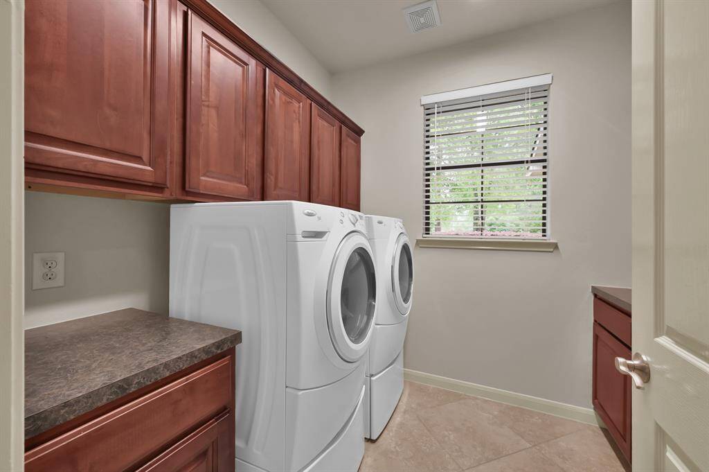Tucked away off the Kitchen and close to the Primary Bedroom, this Laundry Room makes it very convenient to wash clothes. With built-in wood cabinets for all your cleaning and storage needs, two counters for folding or additional uses and room behind the door for a full-size fridge or freezer for overflow food items, you will lack for nothing. There's even a window to keep things bright.