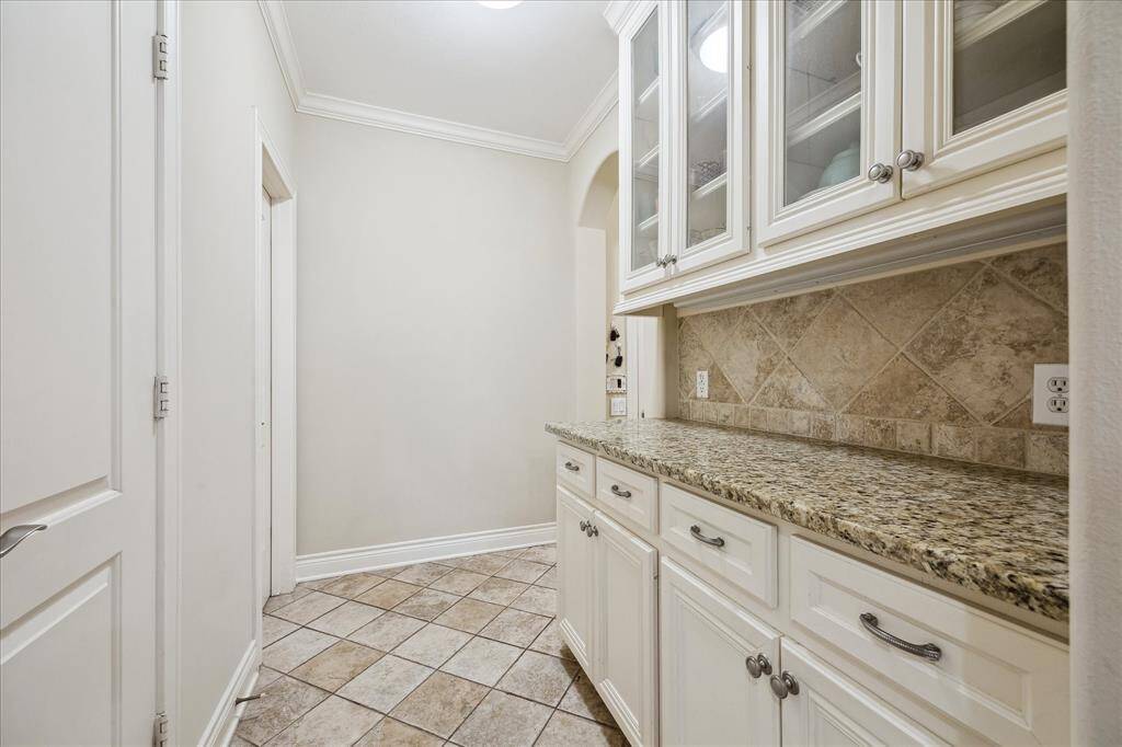 A view of the Butler's Pantry, which includes an additional granite counter with custom cabinetry above and below. The door to the left leads to the 6x3 walk-in pantry.