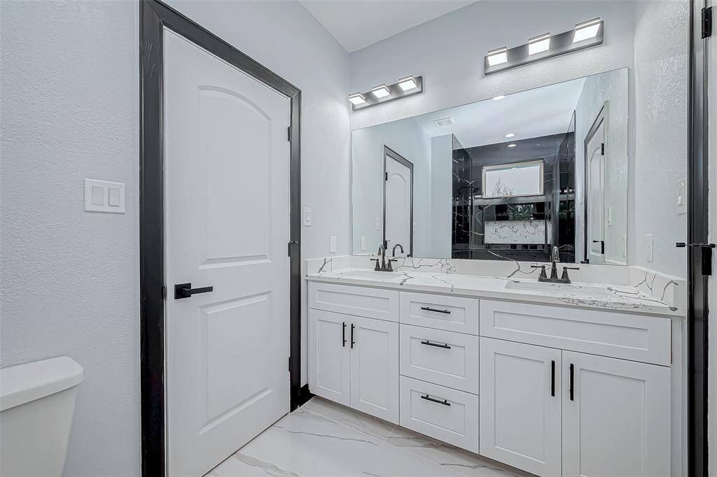 This bathroom, with its bathtub and shower combination, features beautiful finishes, two sinks, and serves two adjacent rooms.