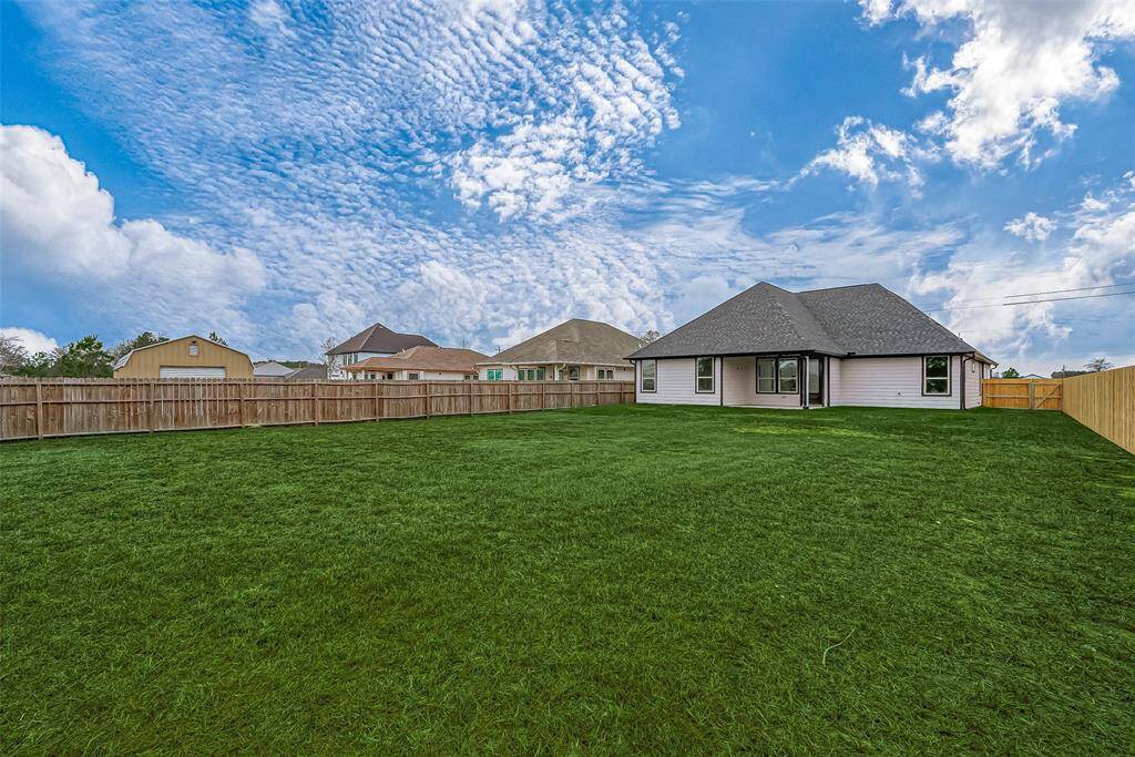 The covered back patio has a ceiling fan, making it more comfortable and inviting for outdoor relaxation.  (Note: The grass has been digitally enhanced to show potential.)